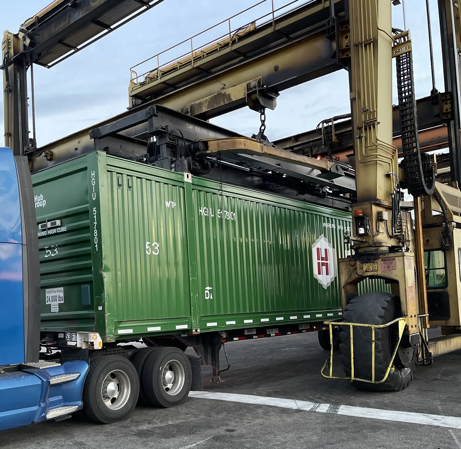 Straddle carrier setting a green 53-foot container onto a chassis at a rail ramp