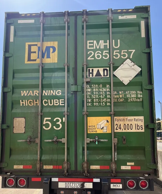 Rear doors of a green 53-foot high cube container on a chassis at a dock
