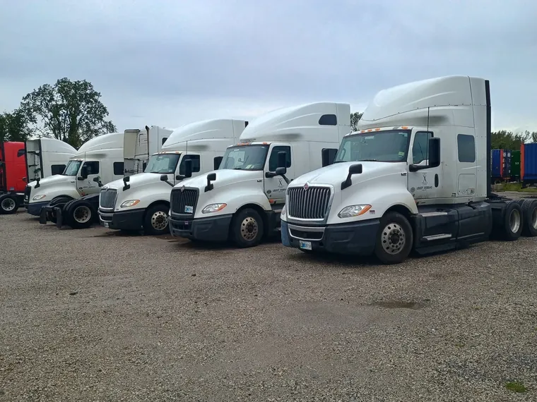 Row of white X Truck Lines International tractors in the yard