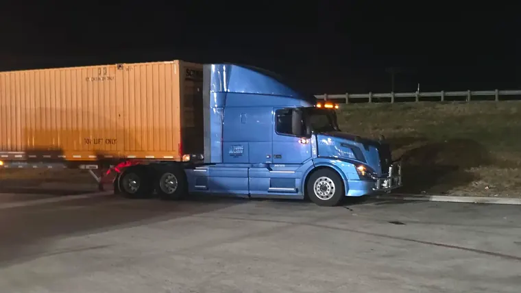 Blue tractor with an intermodal container at night