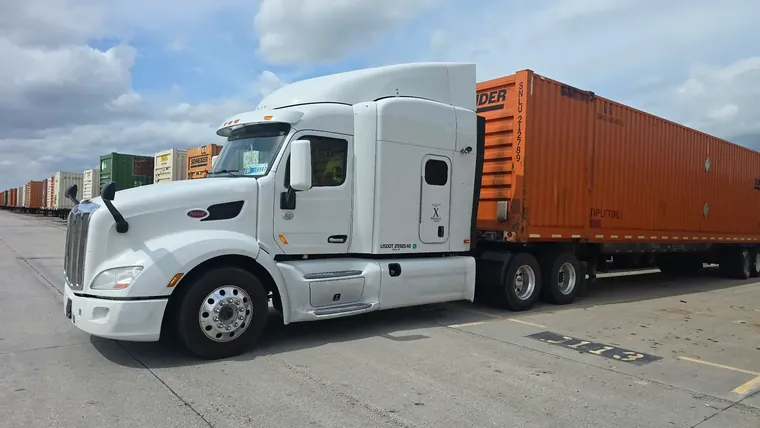 White Peterbilt pulling an orange intermodal container