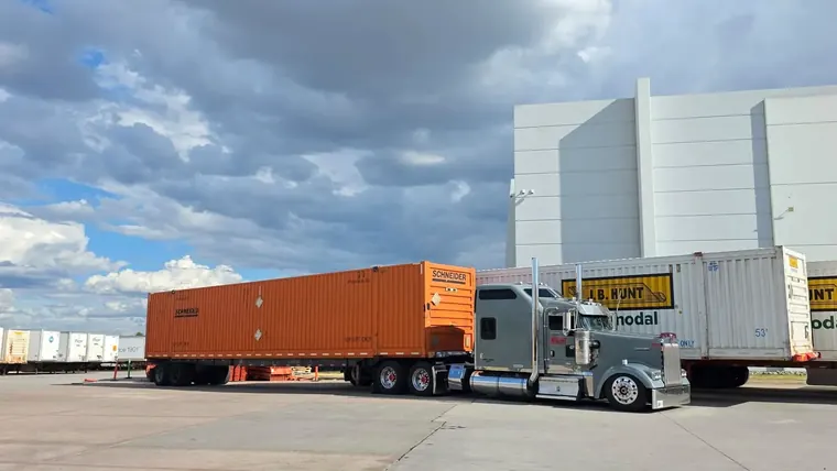 Tractor with an orange container at an intermodal yard