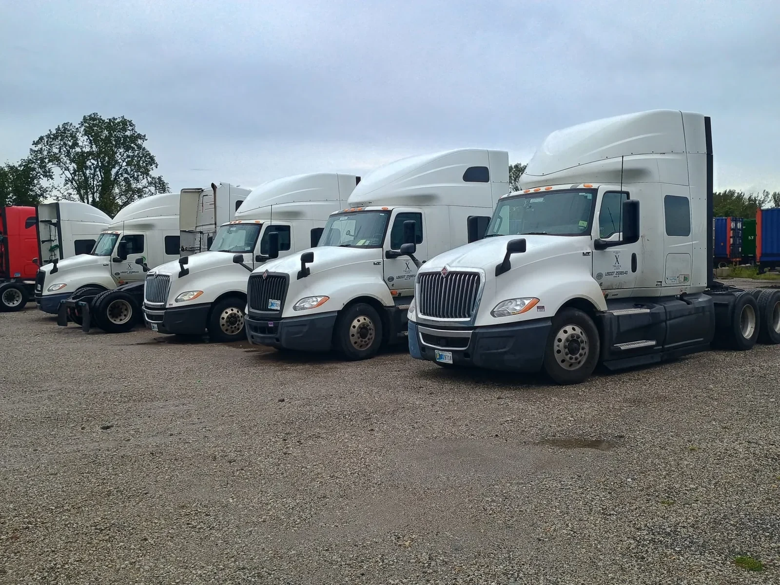 Row of white X Truck Lines International tractors in the yard